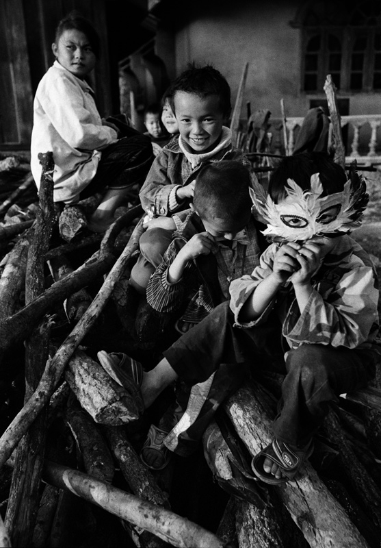 Children playing on piles of wood. Laos - © Carlo Sacco